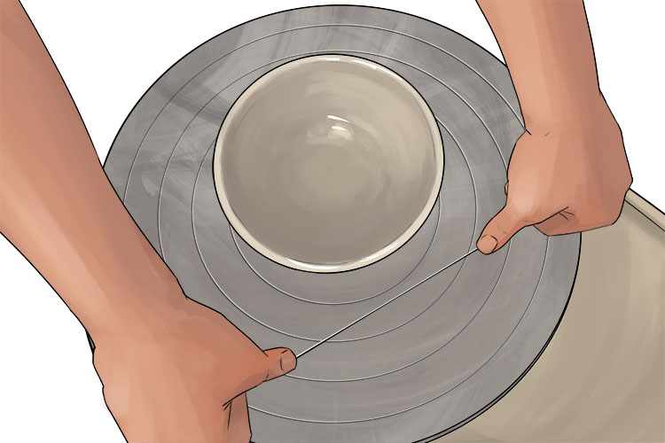 With your wire tool pressed against the surface of the wheel, run the wire under the bowl to separate it from the wheel. Make sure to keep your wire taut so you have a clean cut